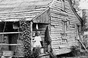 Three people stand on the porch of a wooden structure.