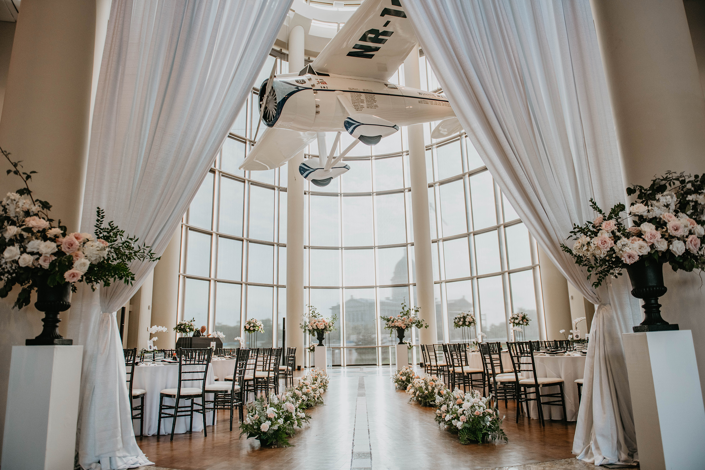 The Devon Great Hall set for a wedding, with numerous floral arrangements, a draped entryway, and tables with white linens.