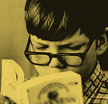 Young boy with glasses reading a book