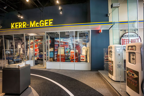 Gas pumps and a yellow lighted Kerr McGee sign.