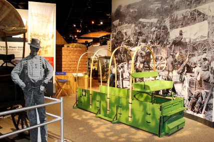 The seats and bed of a wagon, with a large photograph of people in wagons on the wall
