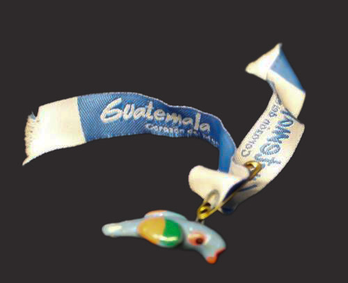 A glass bird attached to a ribbon with the word Guatemala visible. 