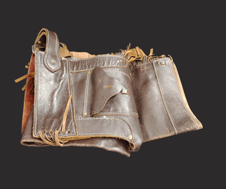 A folded pair of chaps with leather fringe.