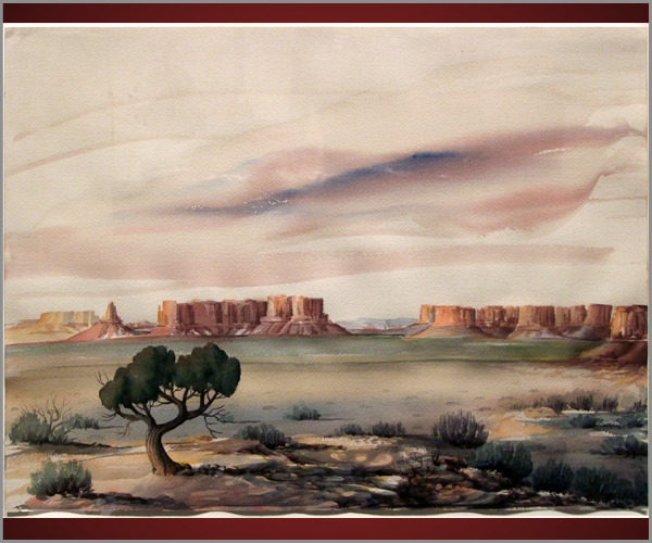 Large formations and buttes stand in the distance beyond a tree with green leaves and scrub brush. The sky is light, with subtle pink and blue waves.